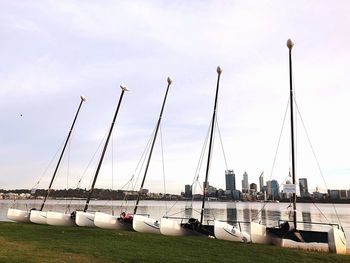 Sailboats moored at harbor against sky