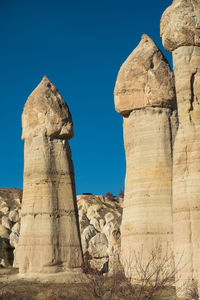 Low angle view of rock formations against clear blue sky