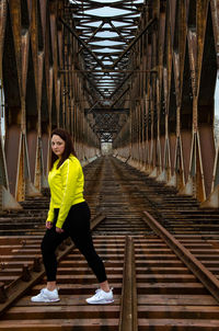 Full length of young woman walking on railway bridge
