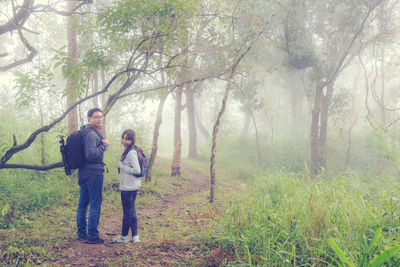 Full length of friends standing by tree in forest