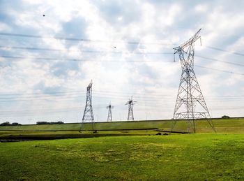 Electricity pylon on field against sky