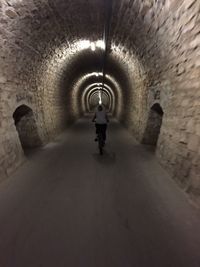 Rear view of man walking in tunnel