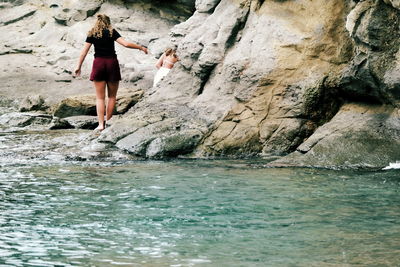 Woman standing on rock by sea