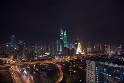 Illuminated petronas towers in city against sky at night