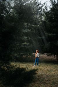 Woman standing on field in forest