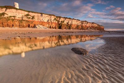 Rock formation on beach against sky