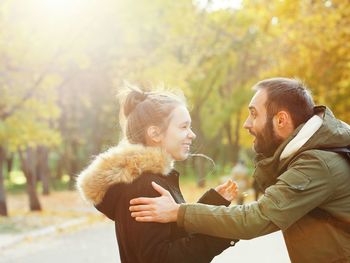 Side view of happy father and daughter standing at park