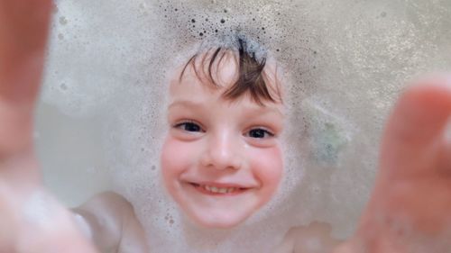 Close-up portrait of happy boy in bathtub