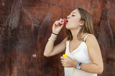 Young woman holding ice cream standing at home