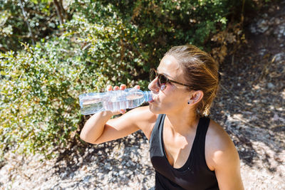 Midsection of woman drinking water from bottle