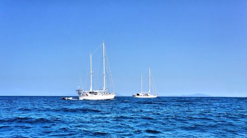 Sailboat sailing on sea against clear blue sky