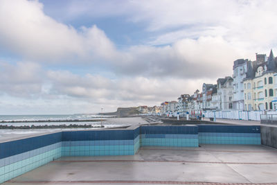 View of swimming pool at beach against cloudy sky
