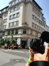 Close-up of man photographing in city against sky