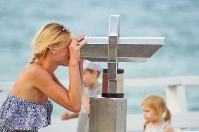 Young woman looking through binoculars at observation point