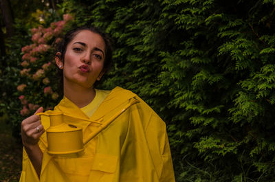 Portrait of beautiful young woman standing against trees