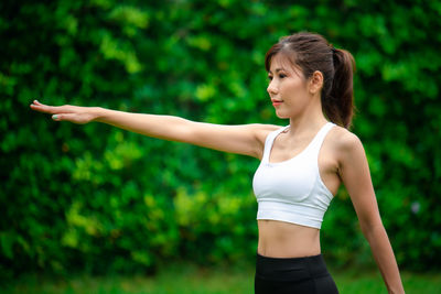 Young woman with arms raised standing against blurred background