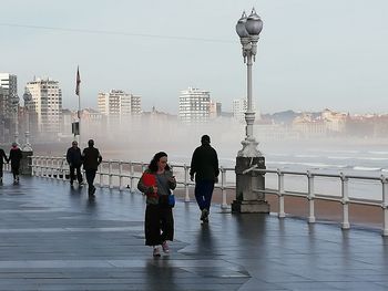 Rear view of people walking on bridge in city