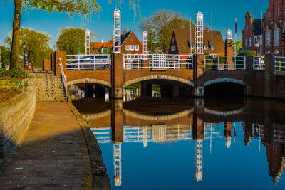 Bridge over river by buildings against sky in city