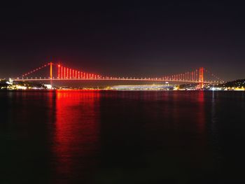 Illuminated bridge over river at night