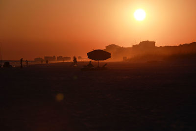 Umbrella sitting on the beach while sunset in florida paints the sky orange