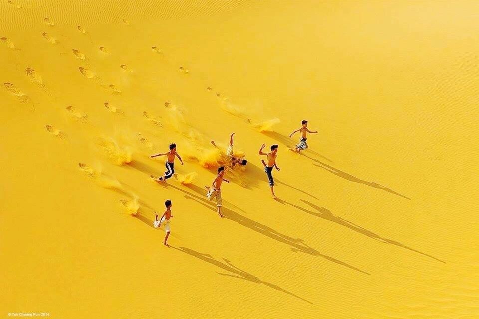 LOW SECTION OF MAN WITH UMBRELLA ON SAND