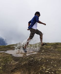 Man running in puddle against sky