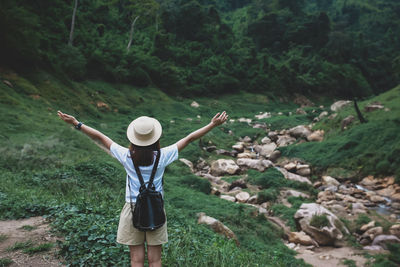 Rear view of woman with arms outstretched standing on landscape