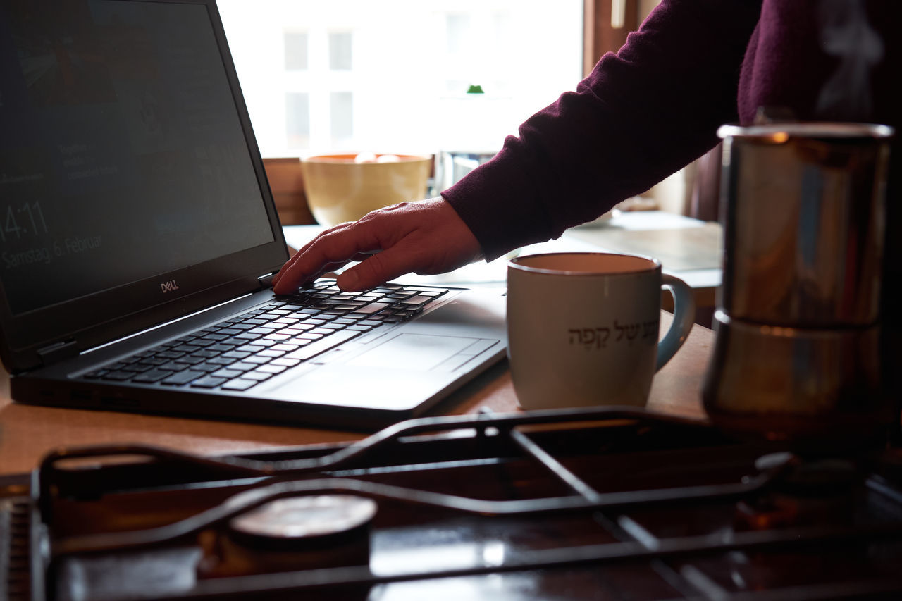 MAN USING LAPTOP ON TABLE AT HOME