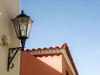 Low angle view of gas light mounted on building against clear sky