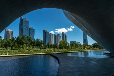 Arch bridge by buildings in city against sky