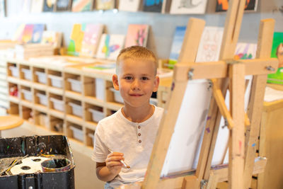 Portrait of smiling boy painting at classroom