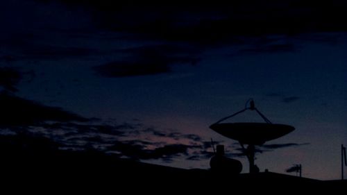 Low angle view of illuminated street lights against sky at dusk
