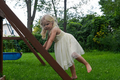 Full length of girl on ladder in playground against trees