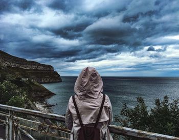 Rear view of woman standing by railing against sea