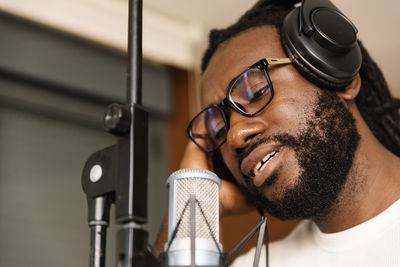 Close-up of man wearing eyeglasses singing in studio