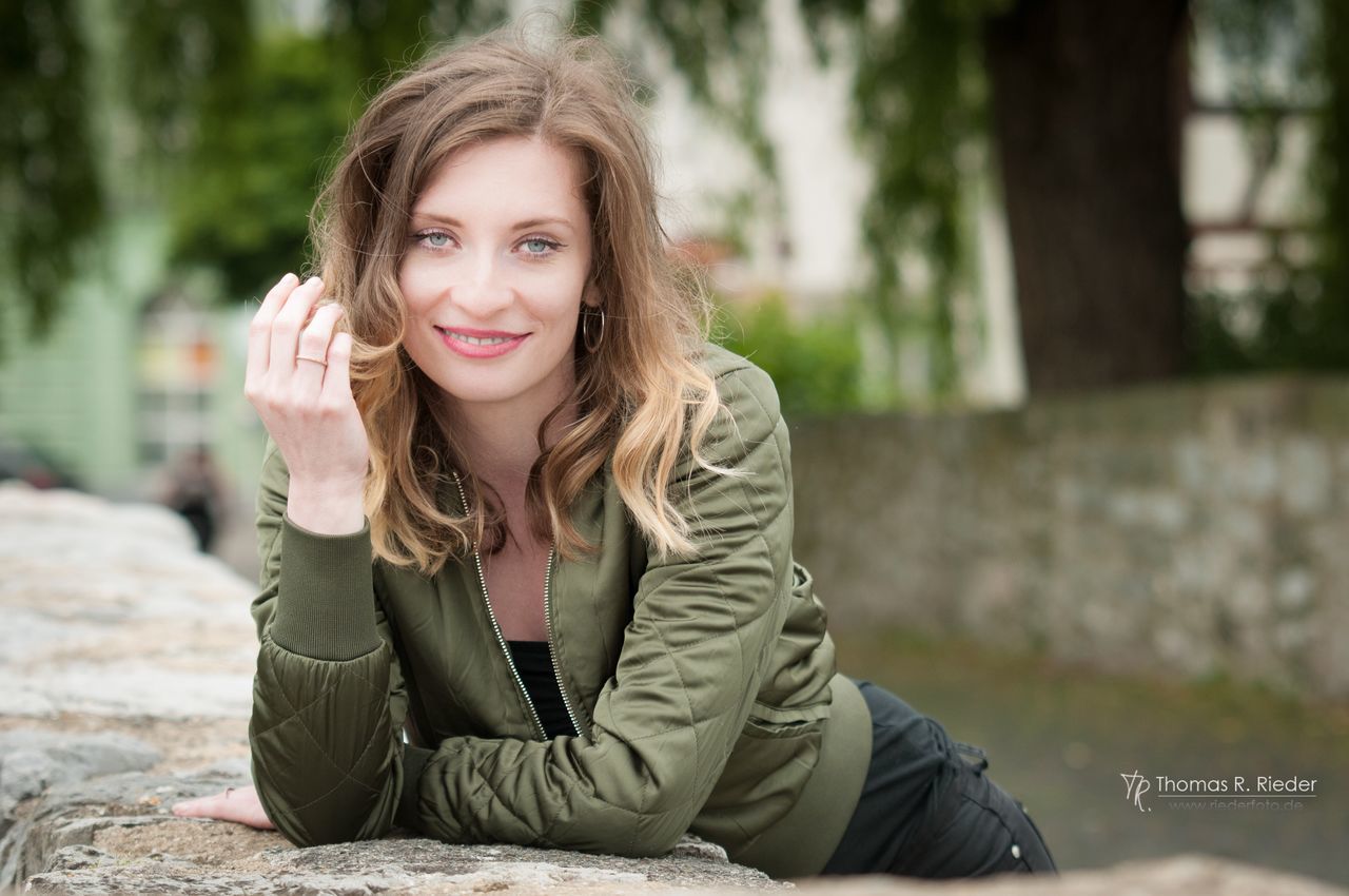 sitting, one person, real people, smiling, focus on foreground, looking at camera, front view, young adult, casual clothing, young women, day, portrait, leisure activity, outdoors, beautiful woman, lifestyles, happiness, blond hair, wireless technology, technology, nature