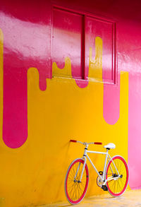 Bicycle parked against yellow wall