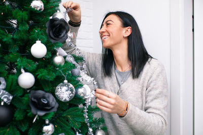 Woman decorating while standing by christmas tree