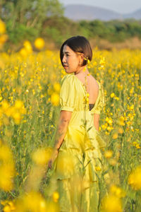 Girl standing on yellow flower field