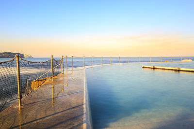 Swimming pool by sea against clear sky