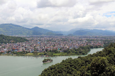 Aerial view of townscape by river against sky