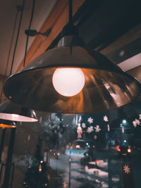 Low angle view of illuminated light bulb hanging on ceiling
