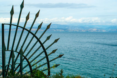 Round fence with spikes with blue sea in background