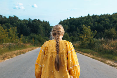 Woman standing on road against trees