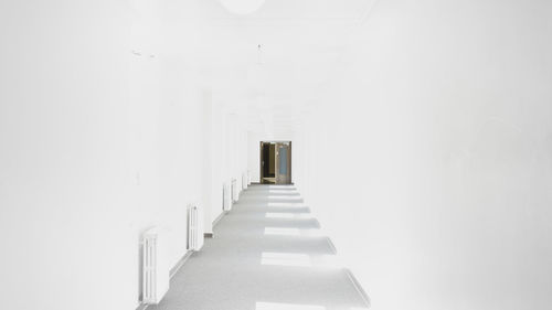 Wide shot of a hall completely white with a door at the end