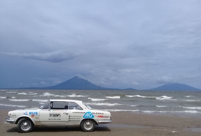 Cars on beach against sky