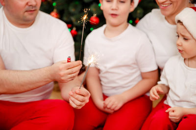 Funny parents and children on xmas with burning sparklers at home.