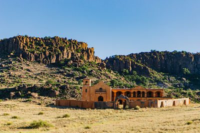 Built structure on landscape against clear blue sky