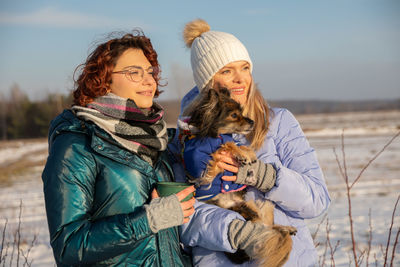 Portrait of smiling friends standing against sky