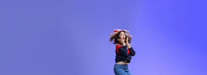 Rear view of woman standing against clear blue sky